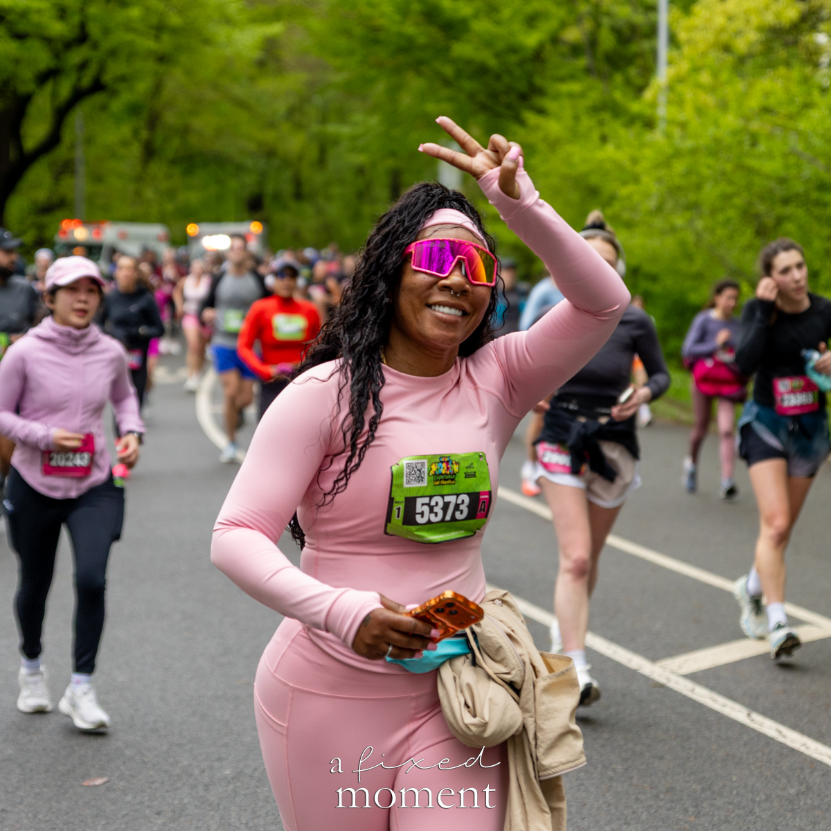Runner in pink outfit gives a peace sign