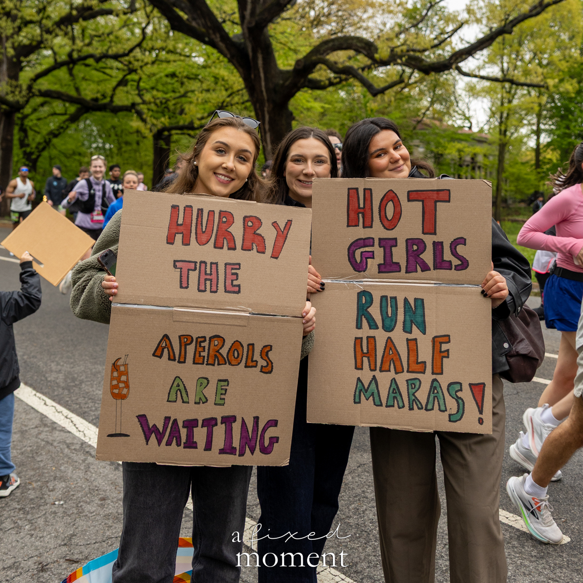 Spectators hold humorous Aperol and half marathon signs during the Brooklyn Experience Half Marathon