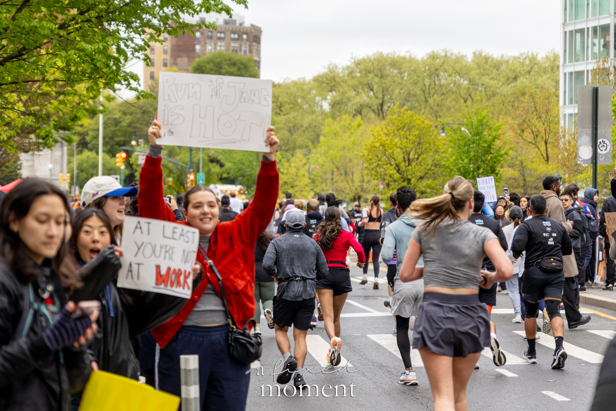 Spectators hold signs as runners pass