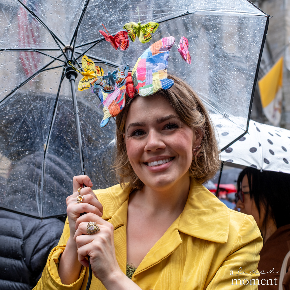 Participant smiling beneath a clear umbrella decorated with butterflies.