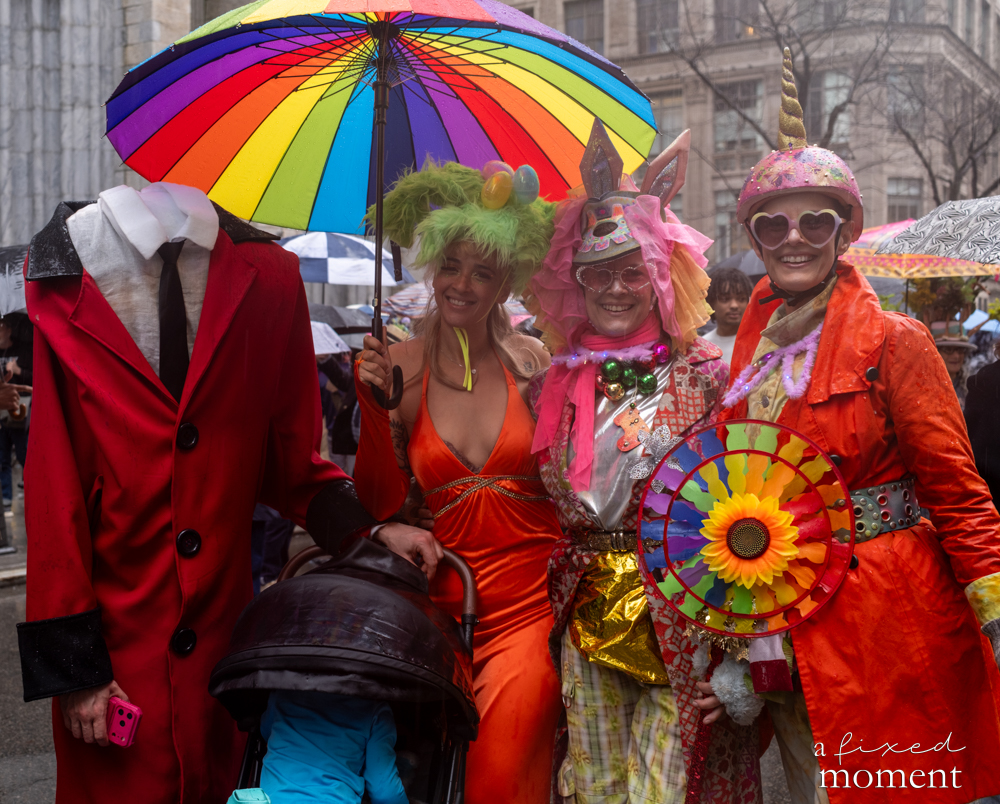 Participants in colorful outfits and umbrellas during the Easter Parade and Bonnet Festival in Manhattan.
