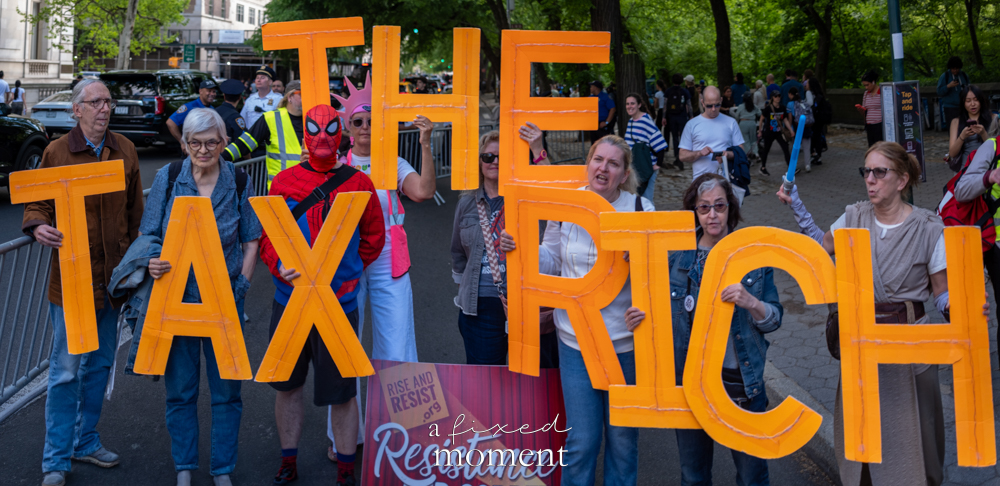 Wide view of Tax the Rich letters and protesters during the Resistance Red Carpet outside the Met Gala in New York City