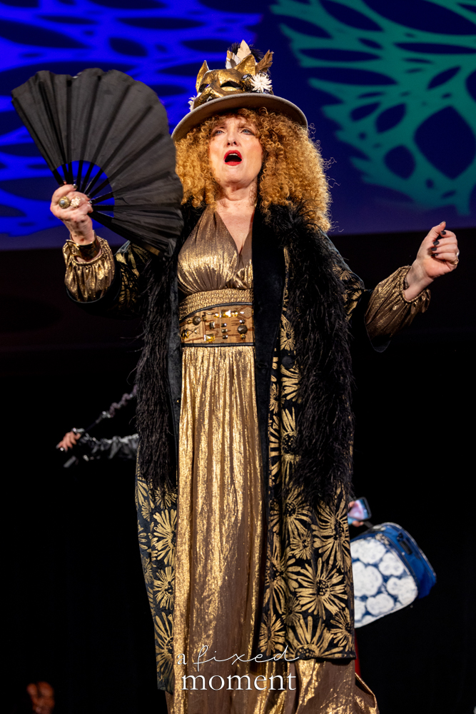 Participant in a gold dress with a black fan on the runway at Brooklyn's 2026 People's Ball