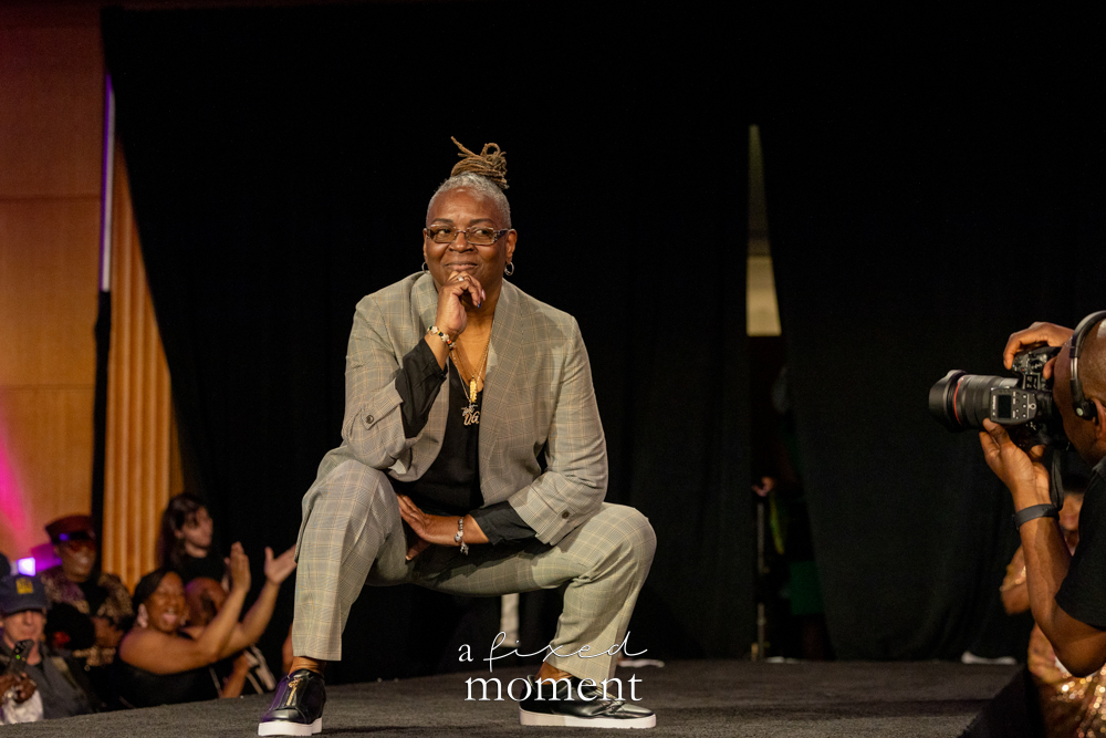 Participant in a gray suit crouches on the runway at Brooklyn's 2026 People's Ball