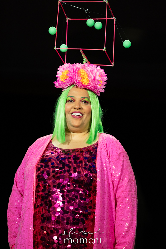 Participant in a pink sequin look with green wig and geometric headpiece on the runway at Brooklyn's 2026 People's Ball