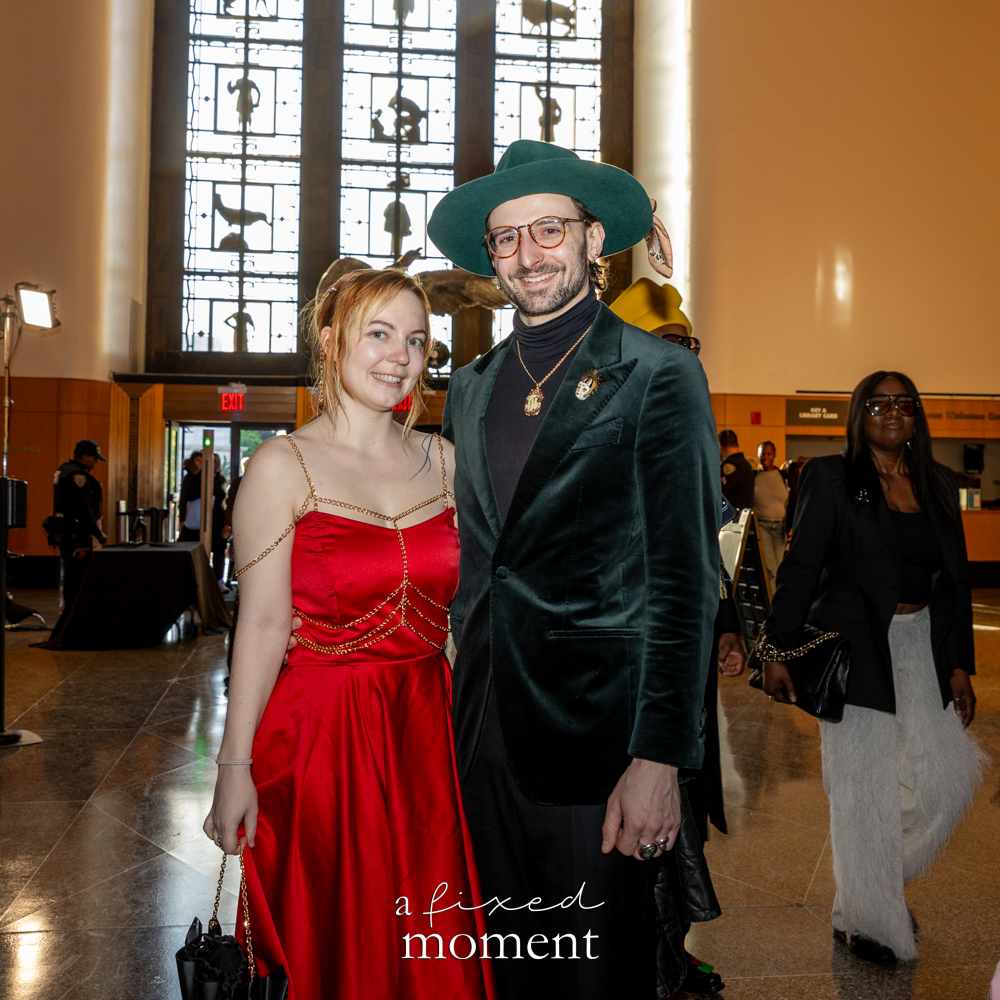 Two attendees in a red dress and green velvet suit pose in the lobby at Brooklyn's 2026 People's Ball