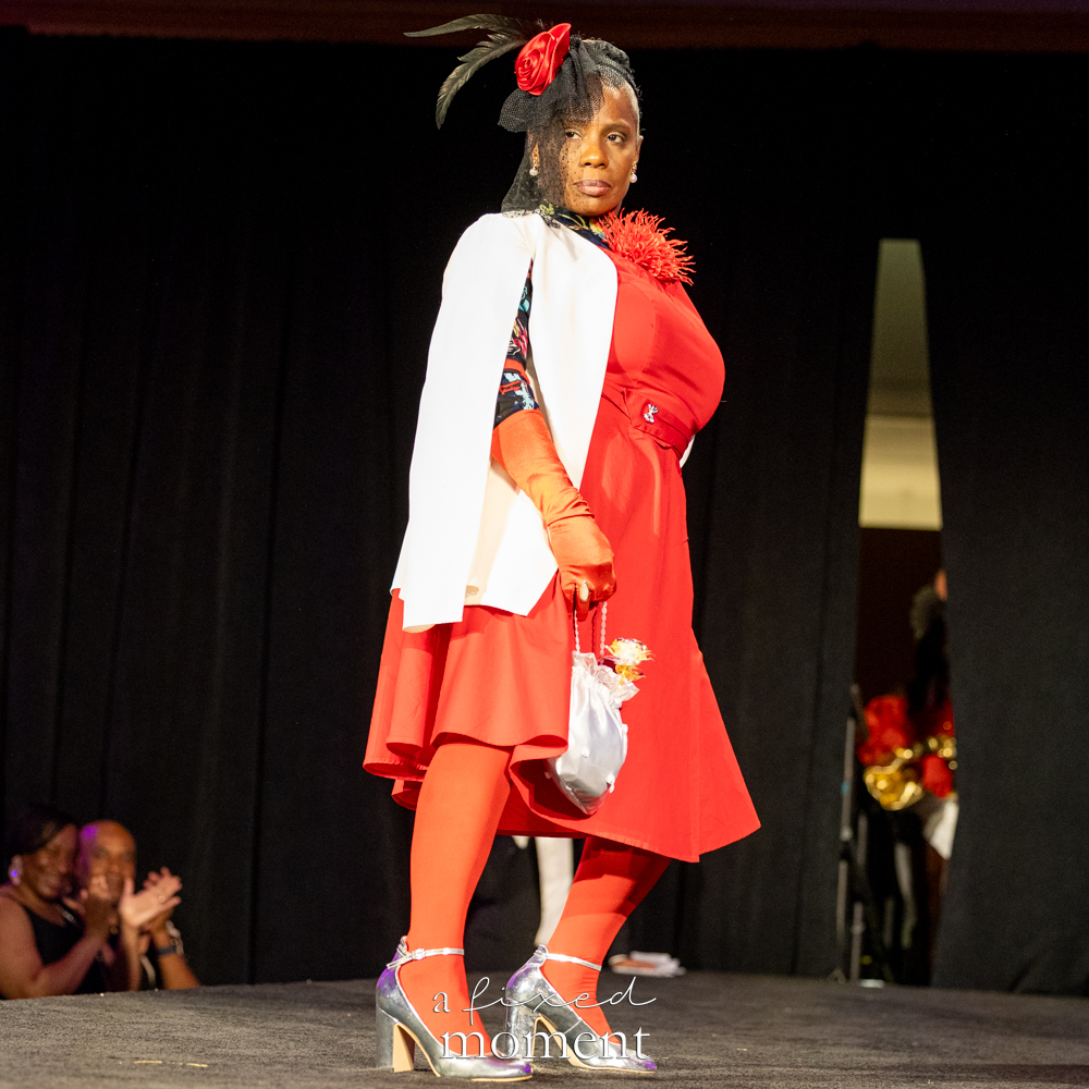 Participant in a red dress and white blazer runway look at Brooklyn's 2026 People's Ball