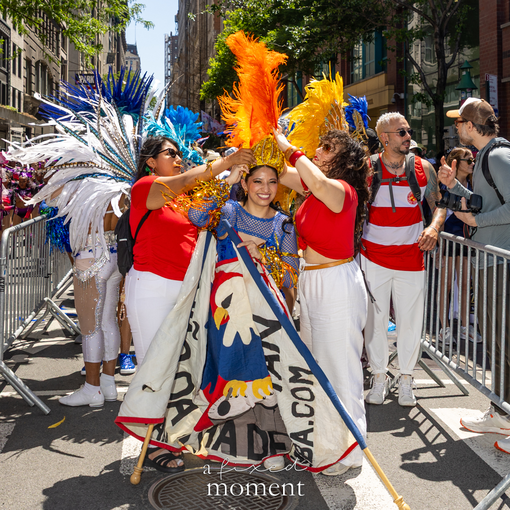 Performer prepares a feathered costume before Dance Parade NYC 2026
