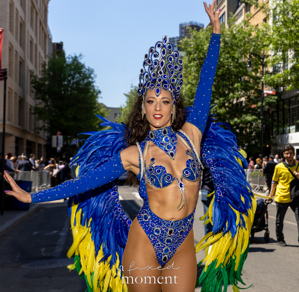 @sambanewyork samba dancer in blue feathered costume during Dance Parade NYC 2026