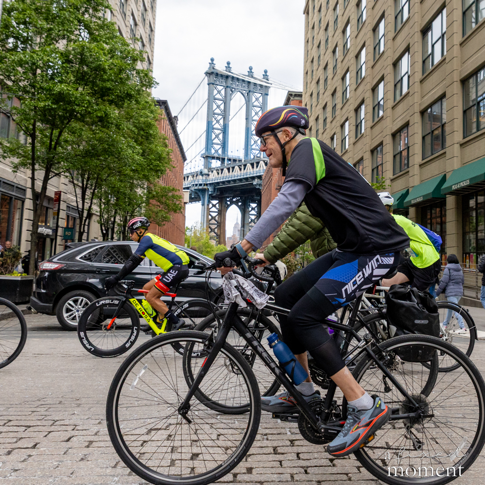 Cyclists ride past the Manhattan Bridge in DUMBO, Brooklyn during the 2026 Five Boro Bike Tour