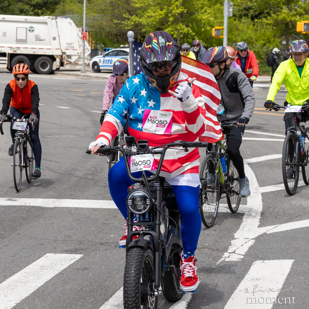 Cyclist in an American flag outfit at an intersection during the Five Boro Bike Tour