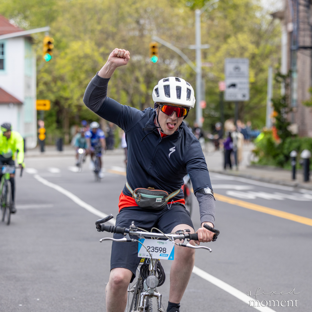Cyclist raises a fist in celebration during the 2026 Five Boro Bike Tour