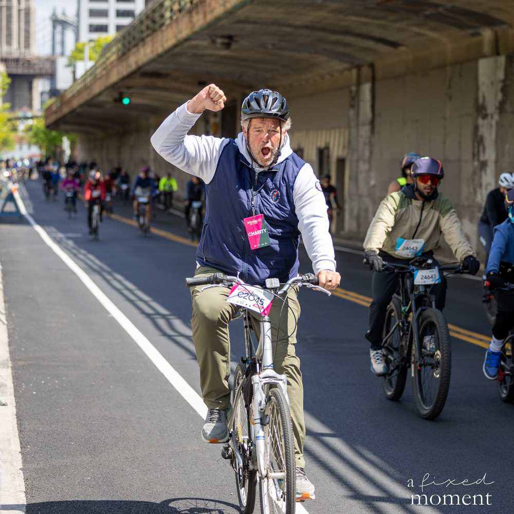 Cyclist raises a fist under an overpass during the 2026 Five Boro Bike Tour