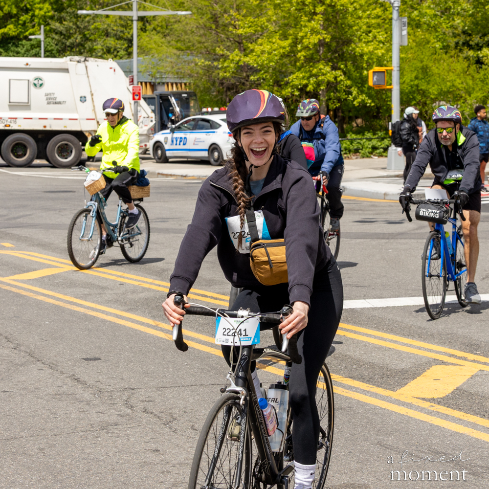 Cyclist smiles at an intersection with NYPD presence during the Five Boro Bike Tour