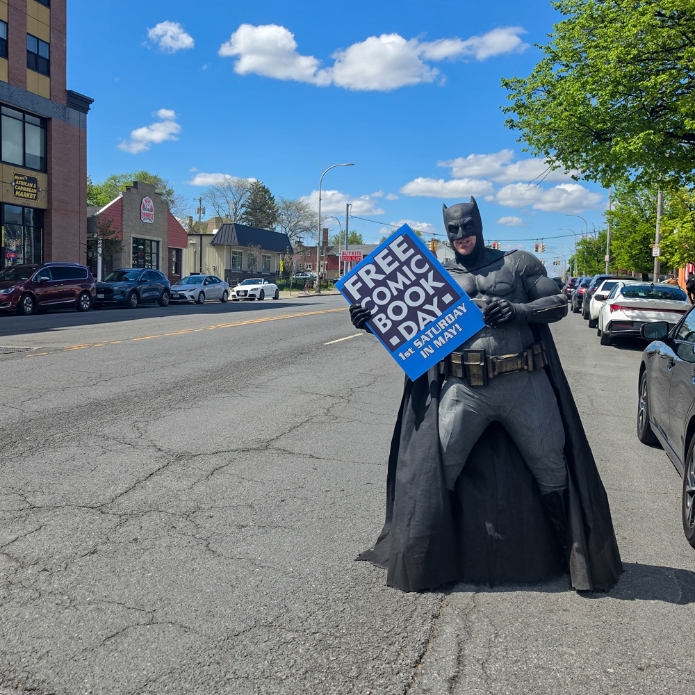 Batman cosplayer poses near a street sign during Free Comic Book Day in Albany, New York