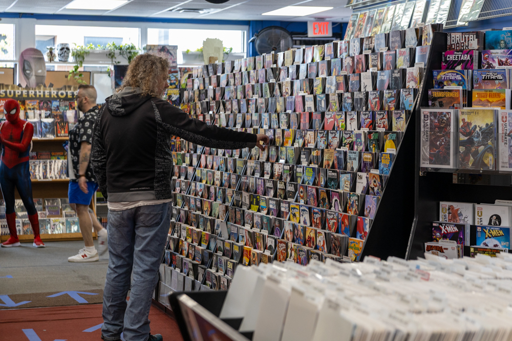A customer browses the comic wall at Earthworld Comics during Free Comic Book Day in Albany, New York