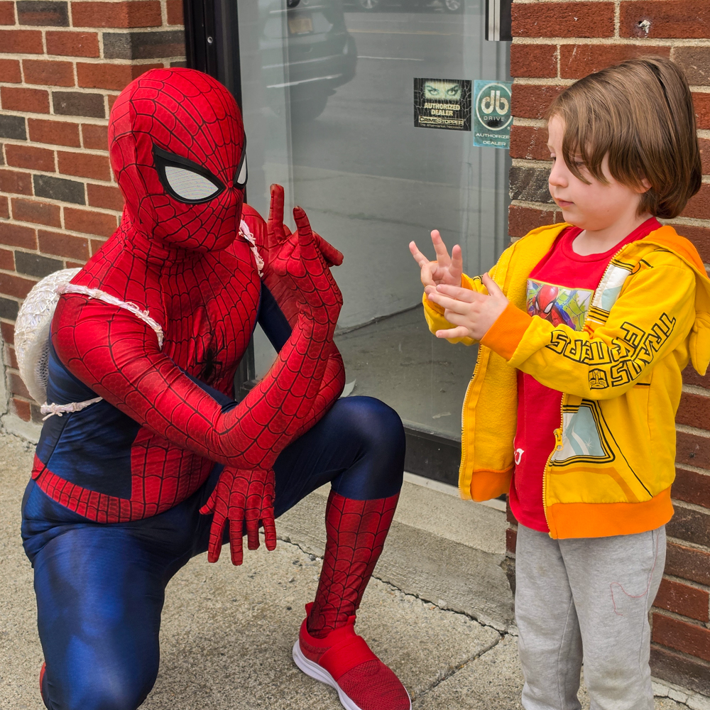 Spiderman cosplayer interacts with a child during Free Comic Book Day at Earthworld Comics