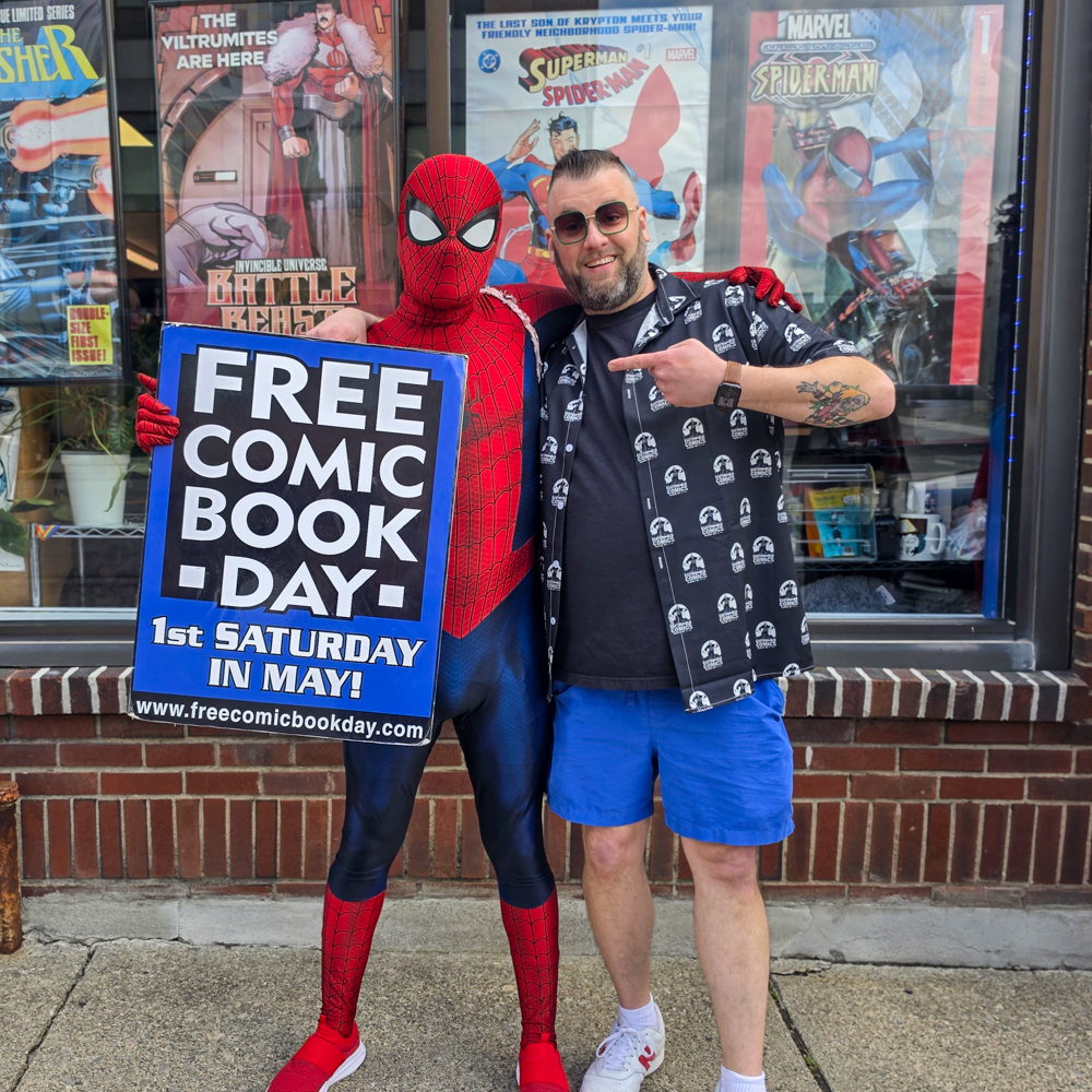 Spiderman cosplayer poses near an Earthworld Comics sign during Free Comic Book Day