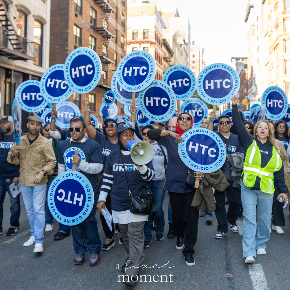Hotel Trades Council members march with blue HTC signs and a megaphone during the May Day Protest in New York City on May 1, 2026