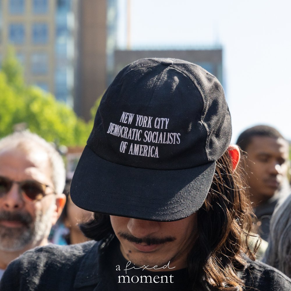 A protest participant wears a Democratic Socialists of America hat
