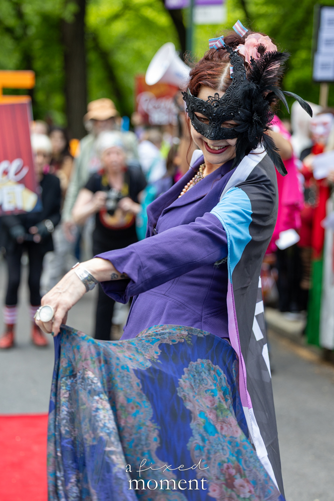 Masked participant in a purple costume poses during the Resistance Red Carpet protest outside the Met Gala