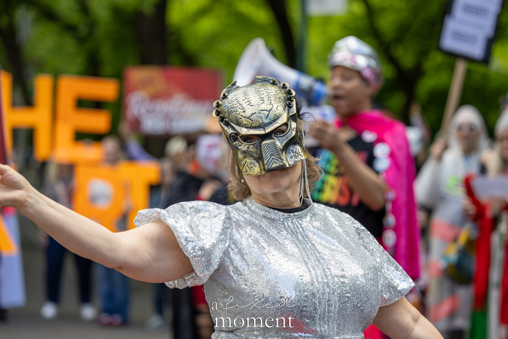 Masked performer in metallic mask and silver sequins during the Resistance Red Carpet protest outside the Met Gala
