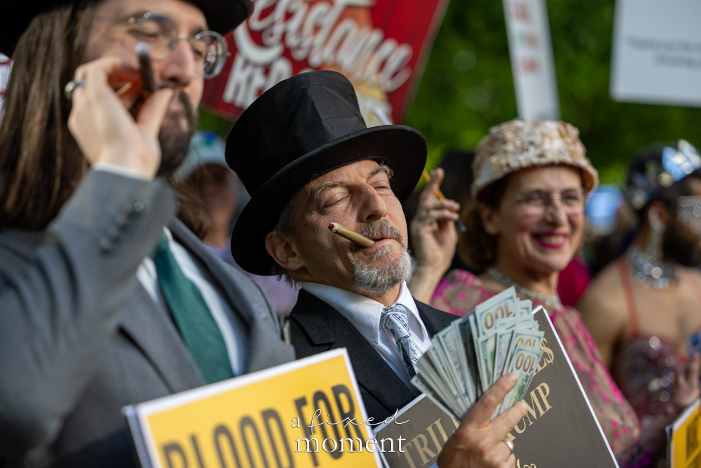 Costumed protesters use fake money, cigars and formalwear to satirize oligarchs outside the Met Gala