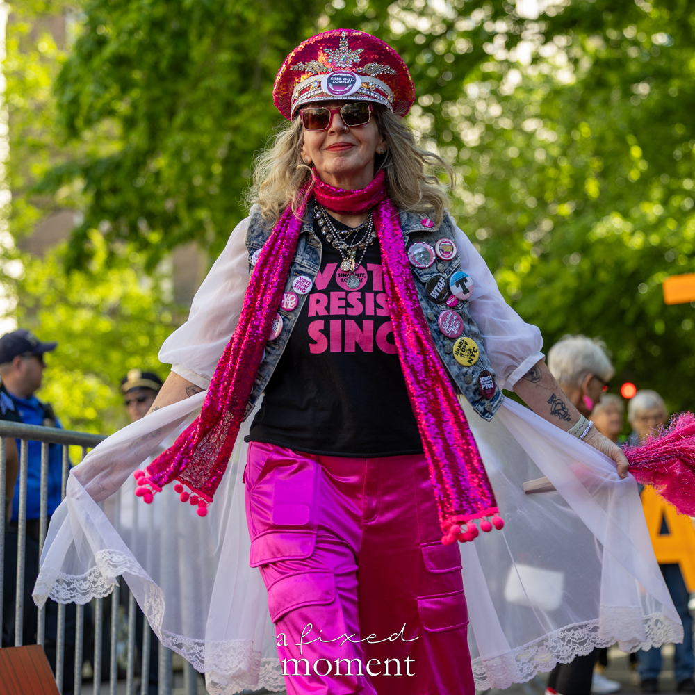 Participant in a pink Resist outfit poses outside the Met Gala during the Rise and Resist protest