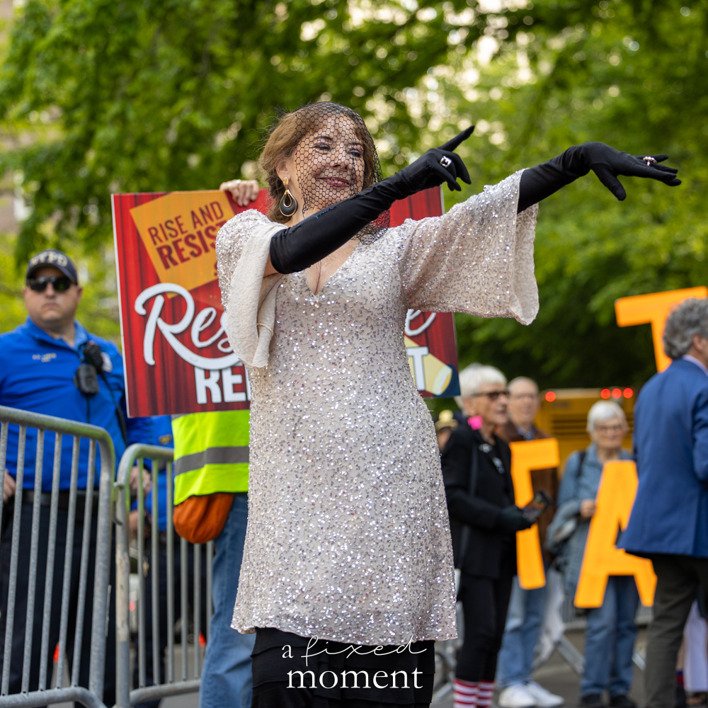 Sequined performer with veil and gloves poses during the Resistance Red Carpet protest outside the Met Gala