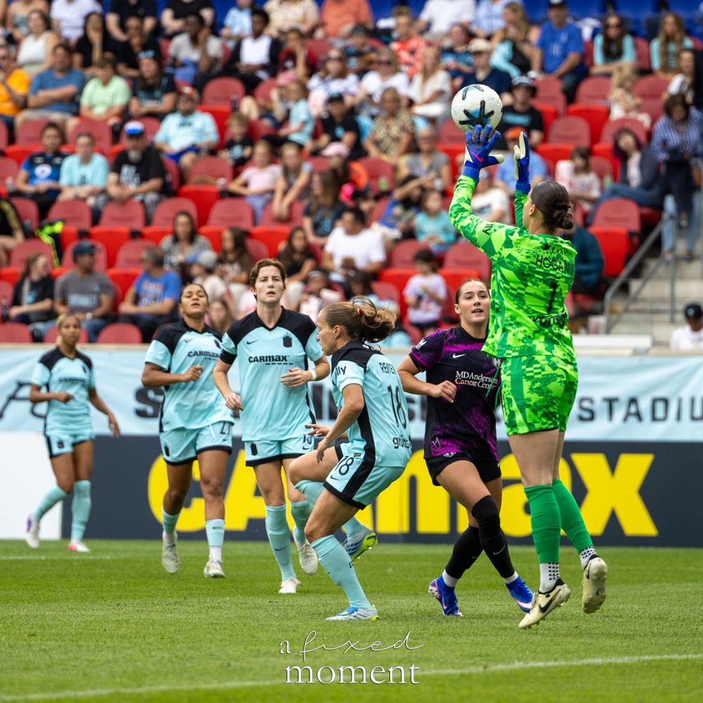Gotham FC @gothamfc goalkeeper in a bright green kit catching the ball above her head as players from Gotham FC and Houston Dash @houstondash watch nearby.