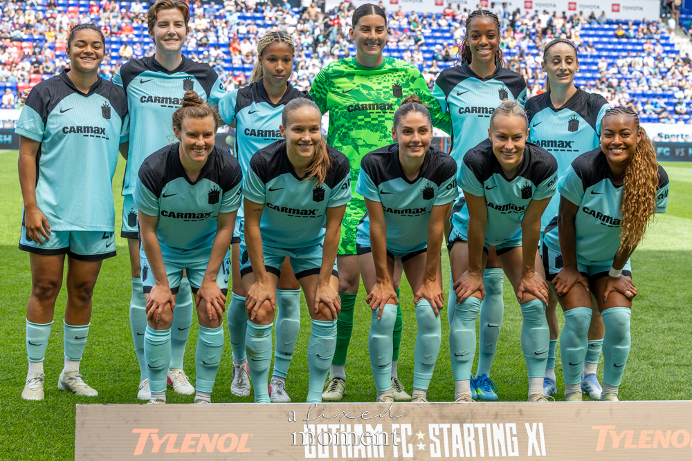 Gotham FC @gothamfc starting XI players posing in light-blue uniforms behind a “GOTHAM FC STARTING XI” sign on the field.