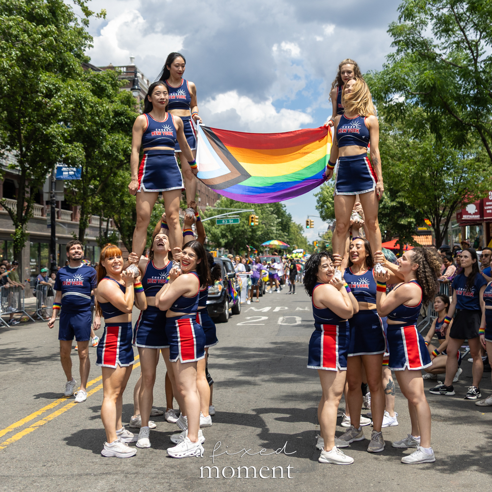 Cheer New York performs a stunt with a large Progress Pride flag during the New Queens Pride Parade in Jackson Heights, Queens.