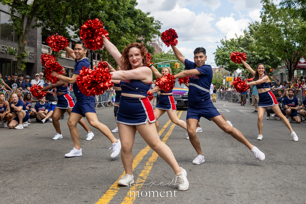 Cheer New York performs with red poms during Queens Pride.