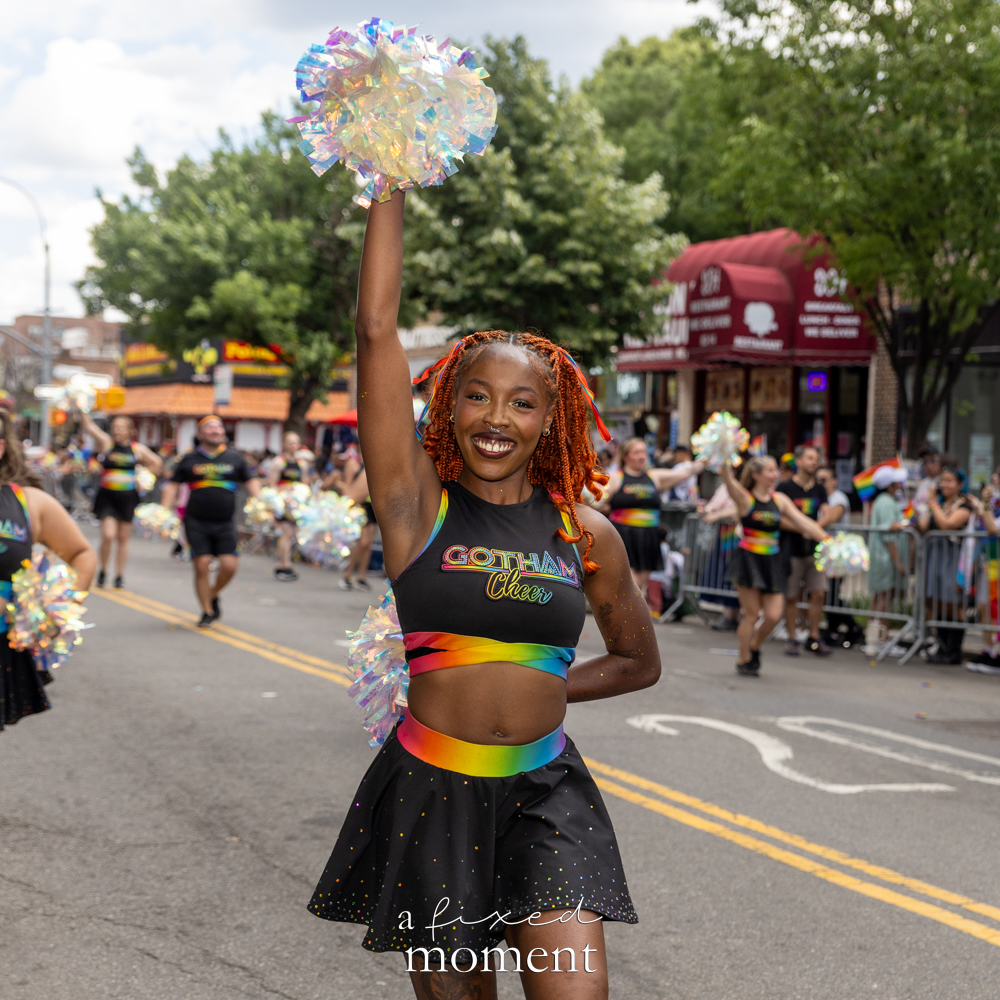 Gotham Cheer Team performer poses with a pom at Queens Pride.