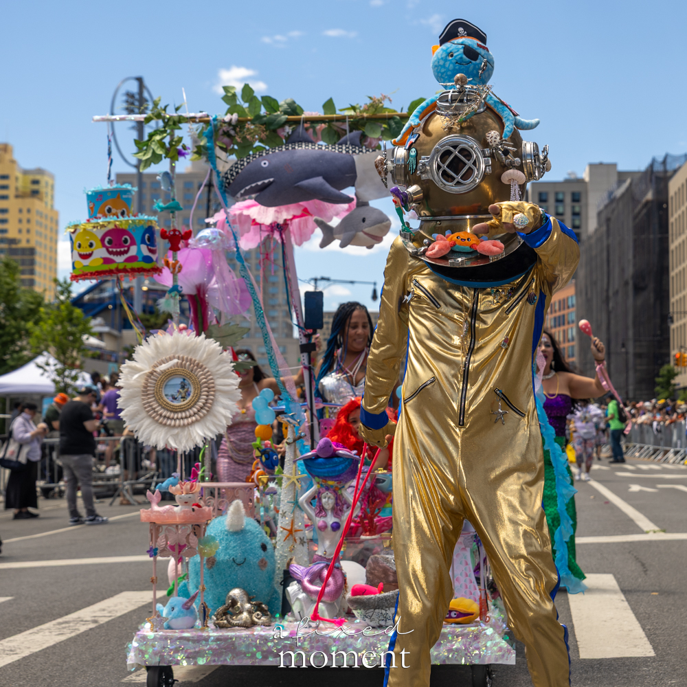 A gold deep-sea diver walks with a handmade ocean-themed float during the Mermaid Parade.
