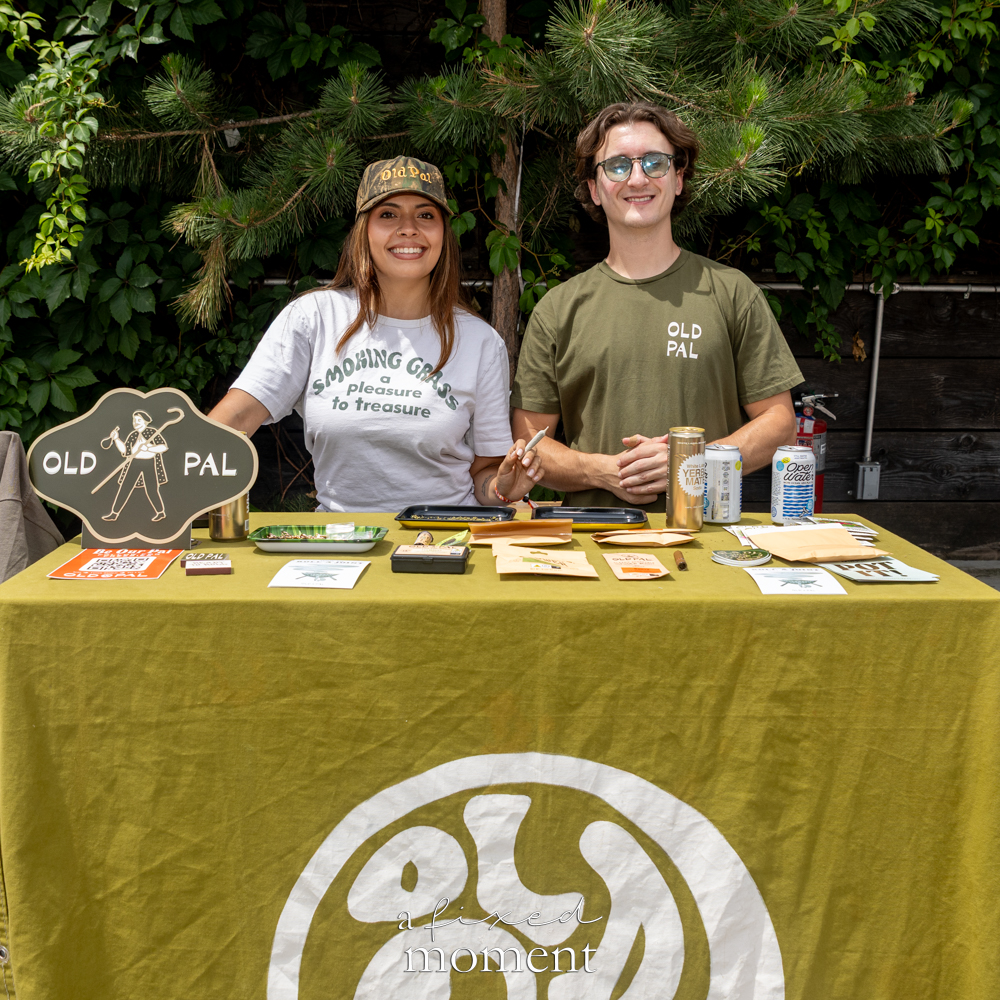 Old Pal vendors stand behind an olive-green cannabis booth table.