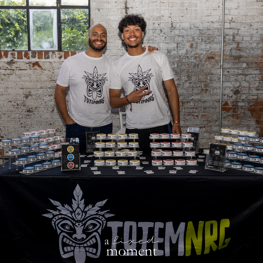 TotemNRG vendors stand behind rows of product containers.