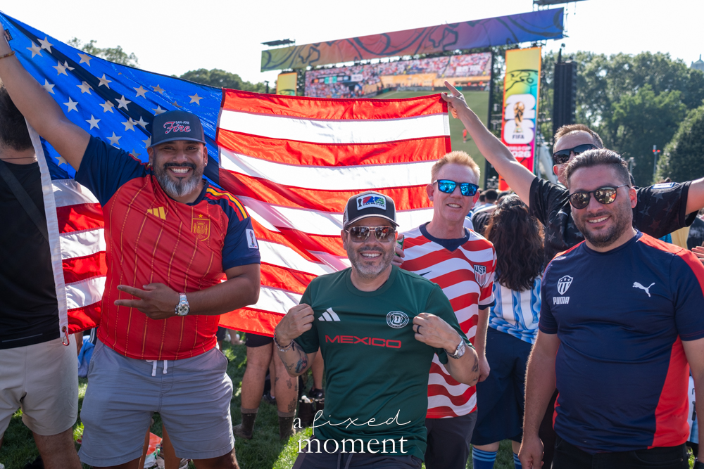 International football supporters in different jerseys beneath a United States flag
