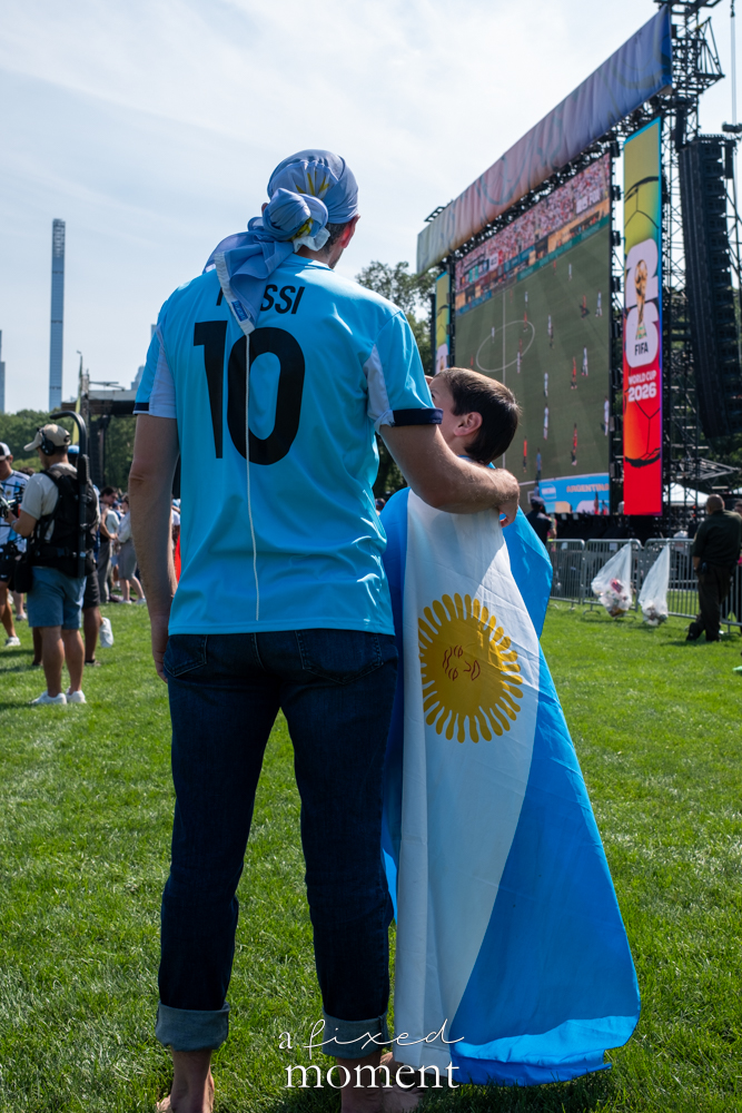 Adult in a Messi jersey beside a child wrapped in an Argentina flag