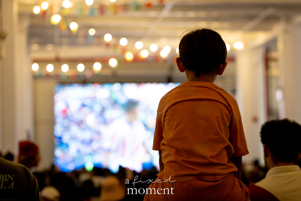 Child watching a World Cup screen above the crowd at House of GOAL in Brooklyn
