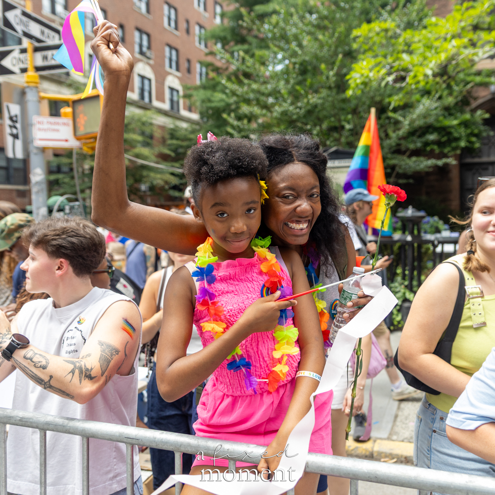 Child and family with Pride flag at barricade during NYC Pride March 2026