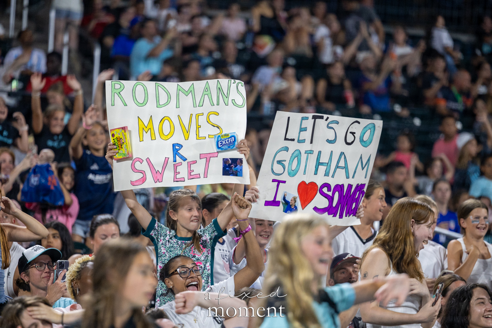Fans holding Trinity Rodman and Emily Sonnett signs at Citi Field