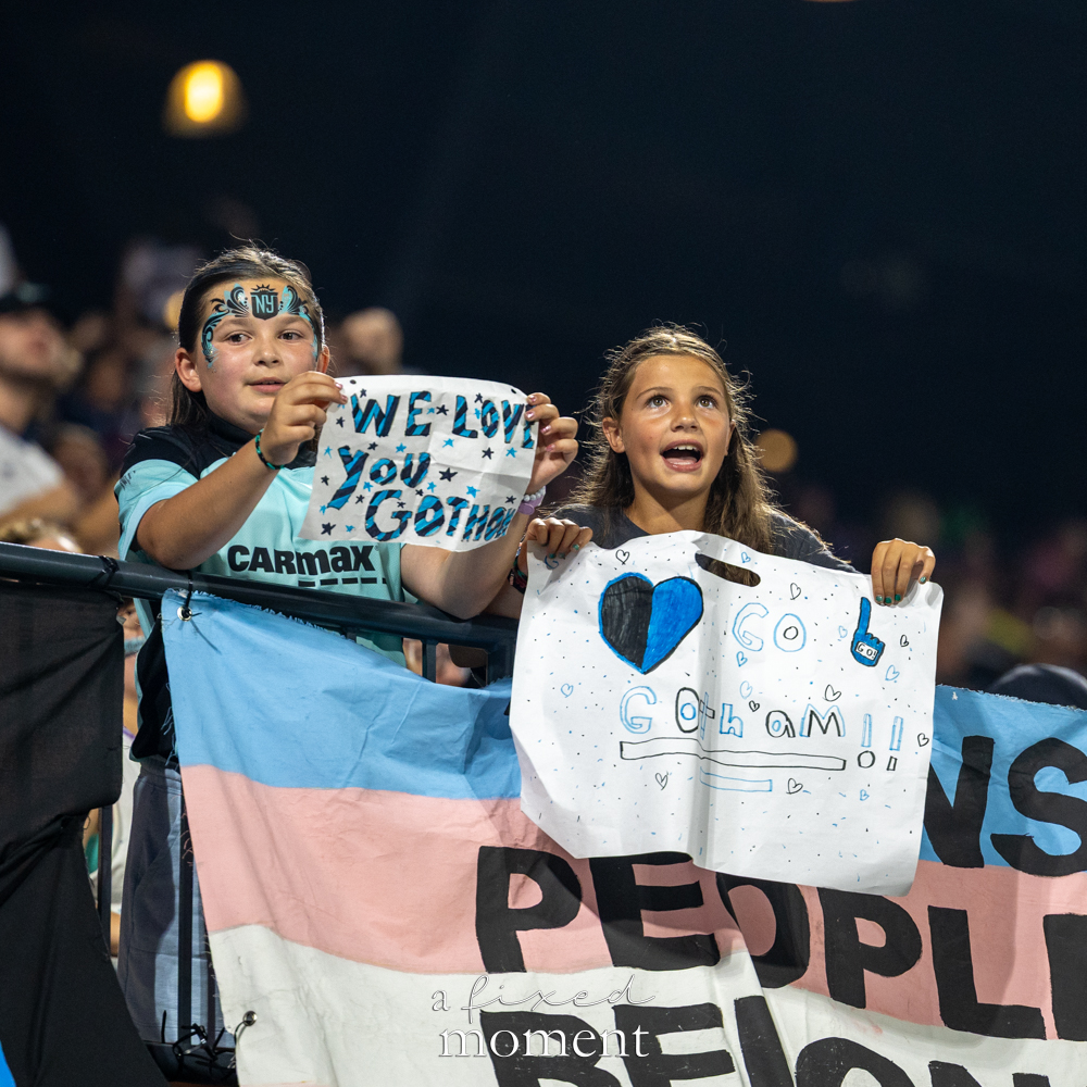 Young Gotham FC supporters holding handmade signs at Citi Field