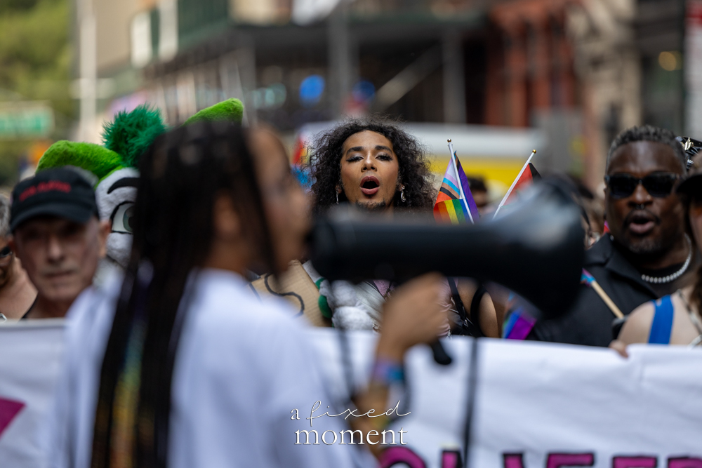 Megaphone in the foreground with Pride flags and crowd at the 2026 Queer Liberation March