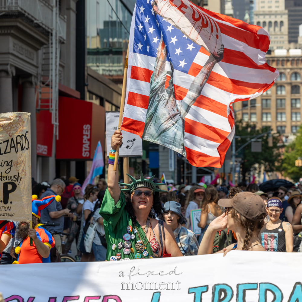 Marcher at the Queer Liberation March carrying a Statue of Liberty flag in New York City