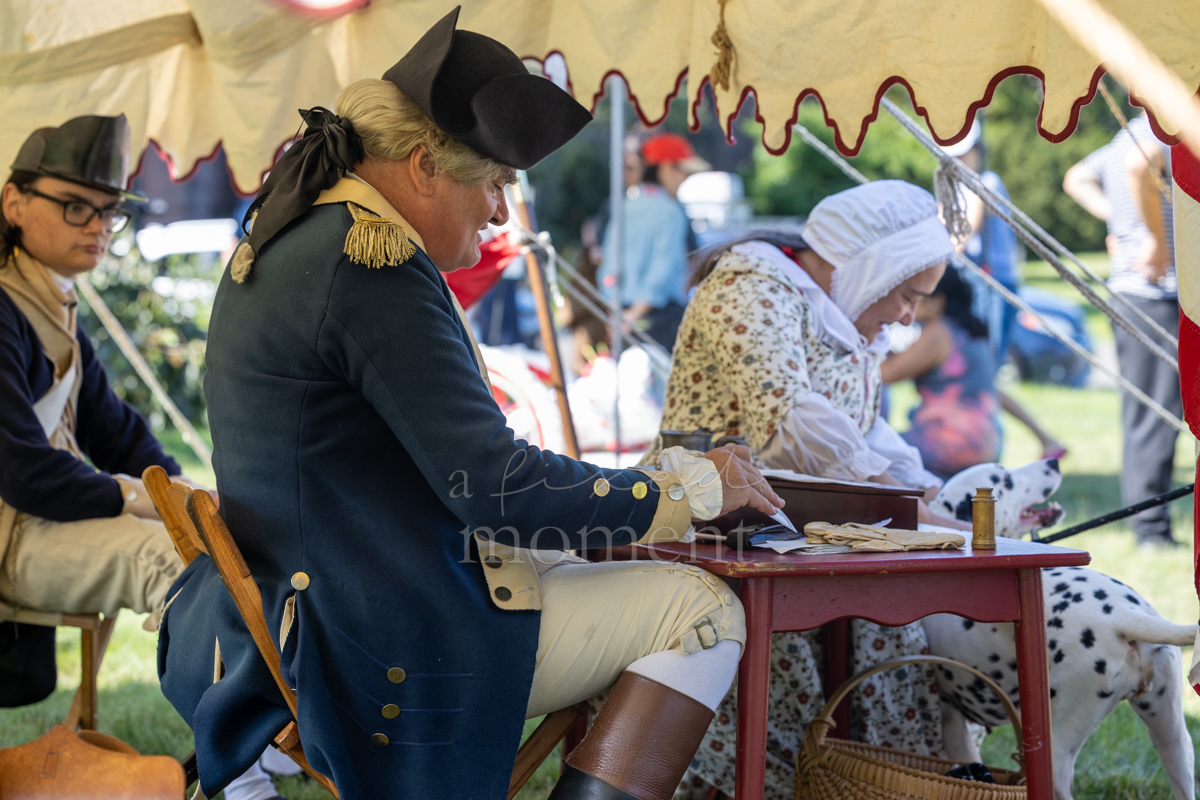 Historical interpreters write at a living-history encampment during the Battle of Brooklyn 250 program
