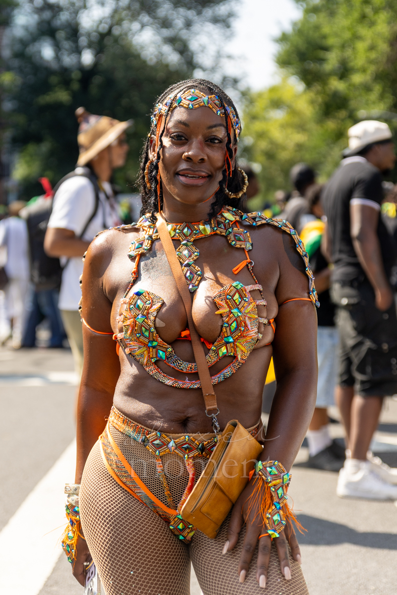 Woman poses in an orange, turquoise and gold beaded carnival costume with a matching headpiece and fishnet tights