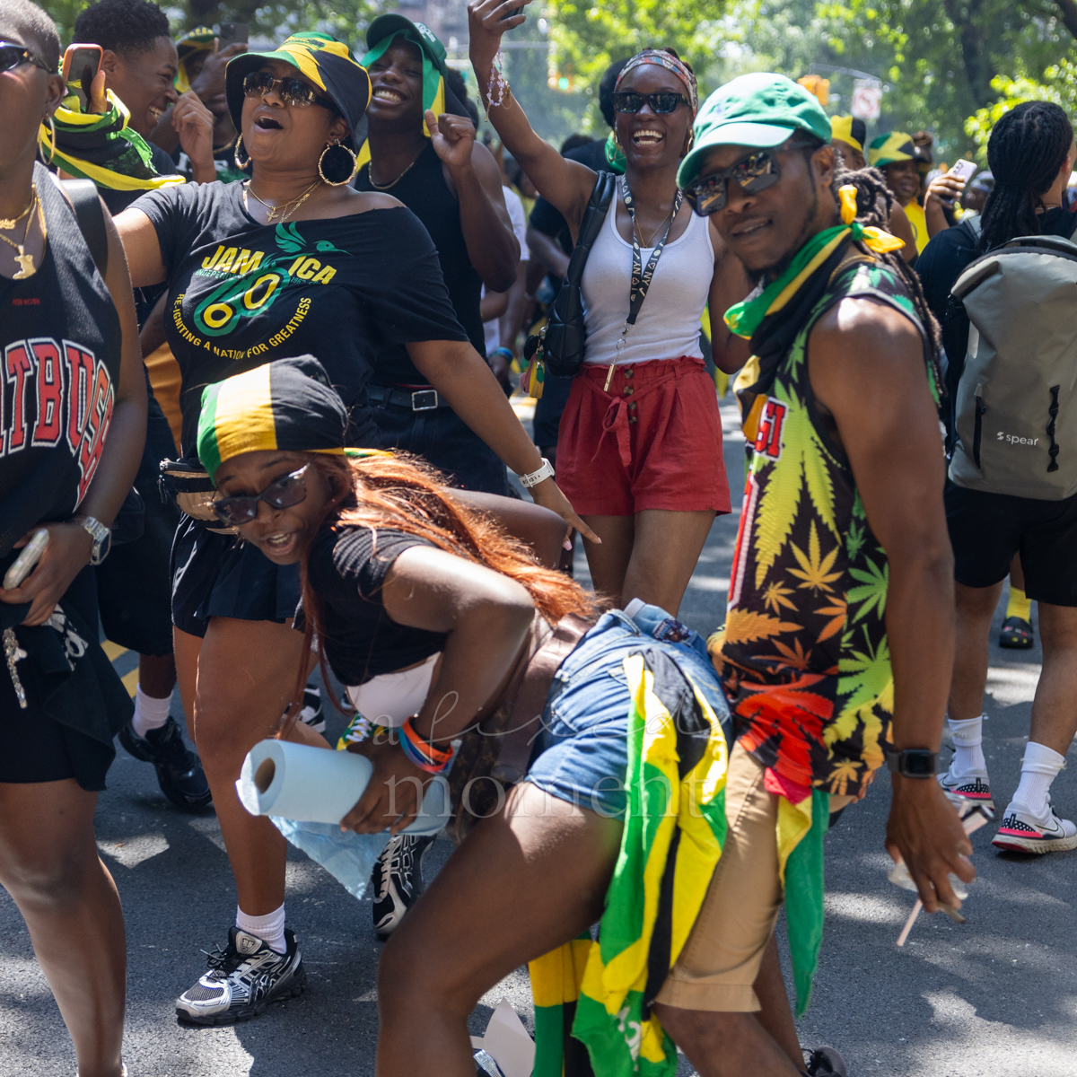 Woman dances in the foreground while cheering paradegoers wearing green, gold and black celebrate around her