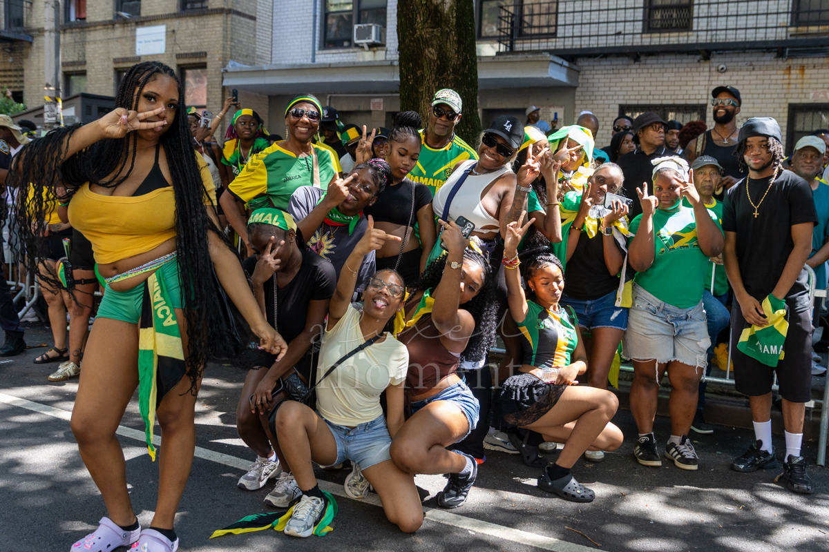 Large group of paradegoers in green, gold and black pose together with several people crouching in front