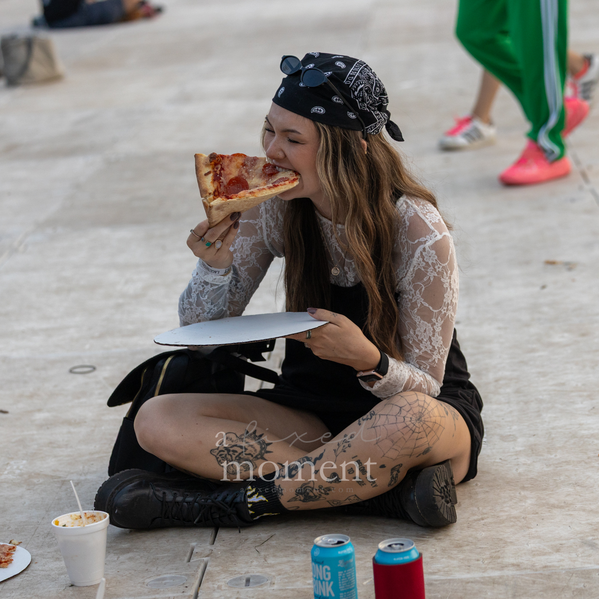 Tattooed festivalgoer eats pizza on the grounds of Riot Fest 2026
